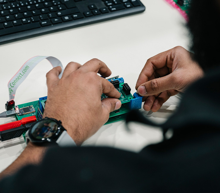 Mitarbeiter arbeitet an einer elektronischen Leiterplatte mit Kabelverbindungen im Entwicklungsbereich von DRD Automation