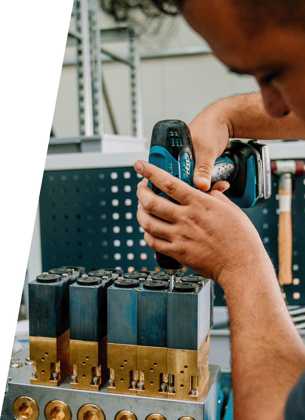 Mitarbeiter montiert mit Akkuschrauber einen hydraulischen Ventilblock in der Fertigung von DRD Automation