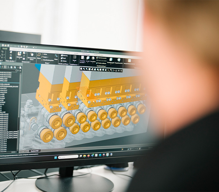 Ingenieur betrachtet am Computer ein 3D-CAD-Modell eines hydraulischen Ventilblocks bei DRD Automation