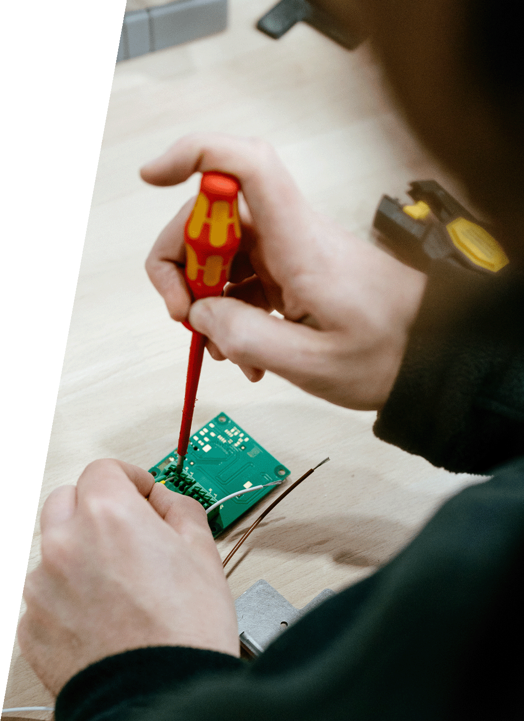 Mitarbeiter montiert eine elektronische Leiterplatte mit einem Schraubendreher in der Werkstatt von DRD Automation