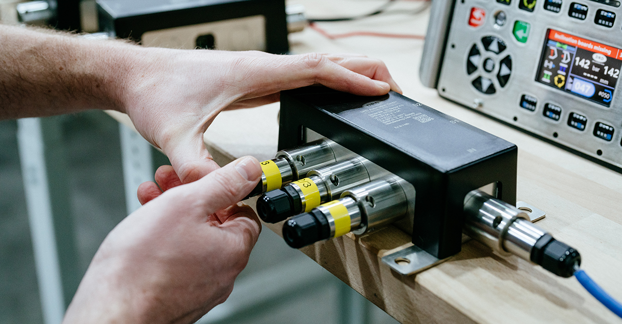 Techniker schließt Hydraulikventile an ein Testmodul in der Werkstatt von DRD Automation an